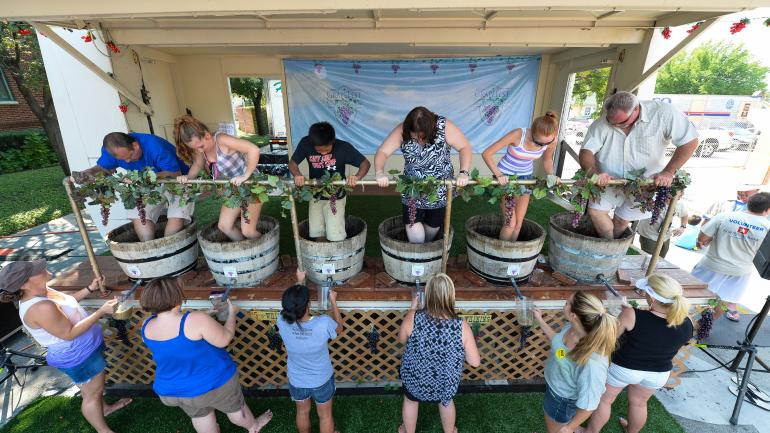 GrapeFest attendees kick off their shoes and compete to make their own juice at the GrapeStomp event in Grapevine