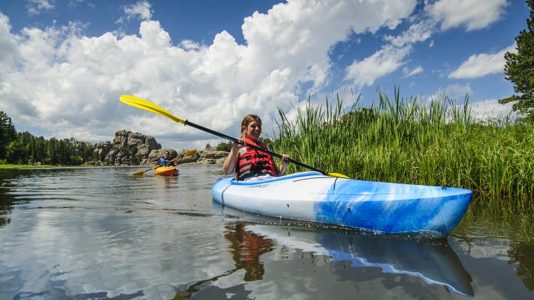 在卡斯特州立公园西尔万湖平静的水面上划着皮划艇，尽情享受休闲静谧的时光。