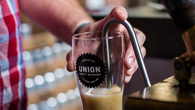 在马里兰州巴尔的摩 Union Craft Brewing 酿酒厂的品酒室品尝桶装啤酒。