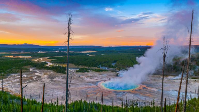 在怀俄明州黄石国家公园内欣赏大棱镜温泉上方的日落美景