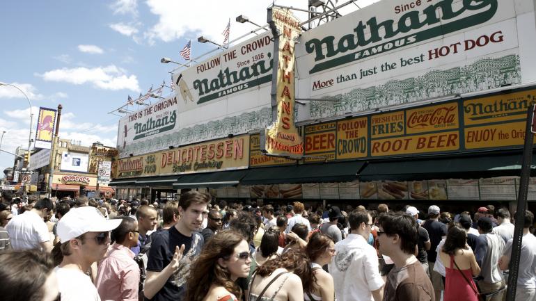 在康尼岛 Nathan's Famous 餐厅排队购买热狗和炸薯条