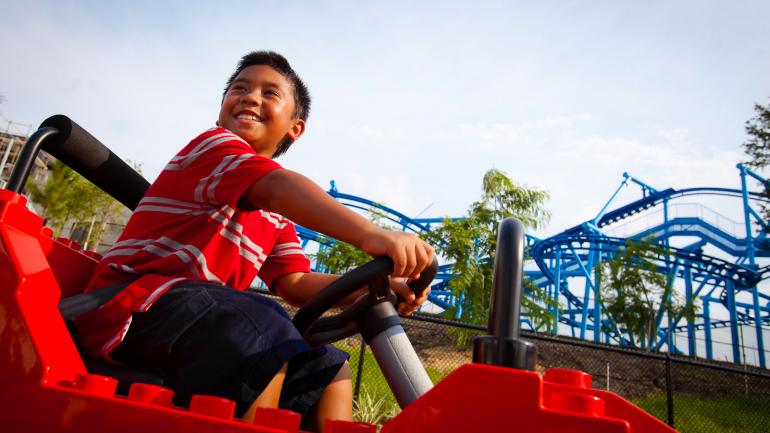 一个开着乐高玩具车的小男孩在乐高乐园尽情玩耍