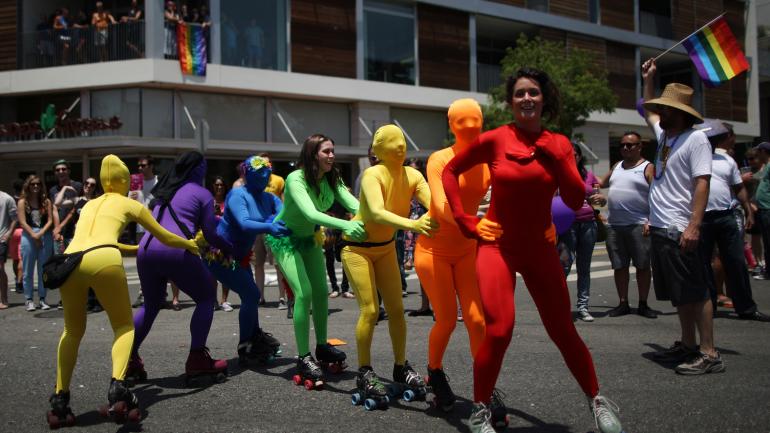 一位女子身着彩虹连体衫在洛杉矶骄傲游行中溜旱冰 一位女子身着彩虹连体衫在洛杉矶骄傲游行中溜旱冰