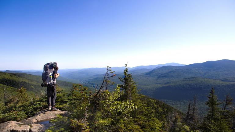 一位正沿着法兰可尼亚州立峡谷公园乡野山路徒步前行的背包客