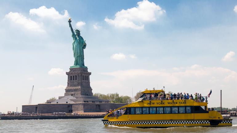 满载乘客的纽约水上出租车驶过自由女神像 满载乘客的纽约水上出租车驶过自由女神像