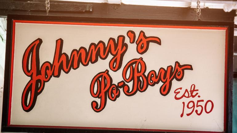 向路人宣传 Johnny's Po-Boy Restaurant 餐厅的标志 向路人宣传 Johnny's Po-Boy Restaurant 餐厅的标志