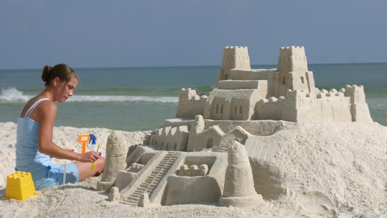 一位年轻的女性正在墨西哥湾海岸的沙滩上做沙雕