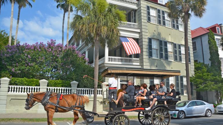 一辆查尔斯顿马车走在历史悠久的炮台街,您可以欣赏到 18 世纪佐治亚风格的排屋 一辆查尔斯顿马车走在历史悠久的炮台街,您可以欣赏到 18 世纪佐治亚风格的排屋