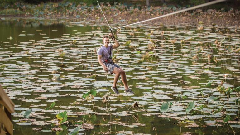 前往谢尔比农场公园的 Go Ape Zip Line & Treetop Adventure 冒险乐园,从高处飞跃满是睡莲的池塘 前往谢尔比农场公园的 Go Ape Zip Line & Treetop Adventure 冒险乐园,从高处飞跃满是睡莲的池塘