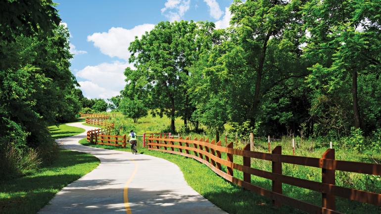 一位公路自行车手蜿蜒盘旋在 Razorback Regional Greenway 绿道上 一位公路自行车手蜿蜒盘旋在 Razorback Regional Greenway 绿道上