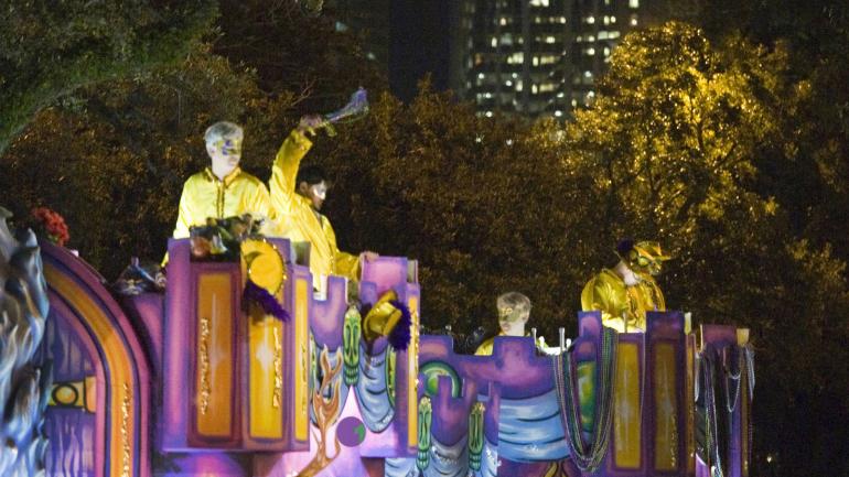 一行五彩斑斓的游行者像观众们抛掷串珠