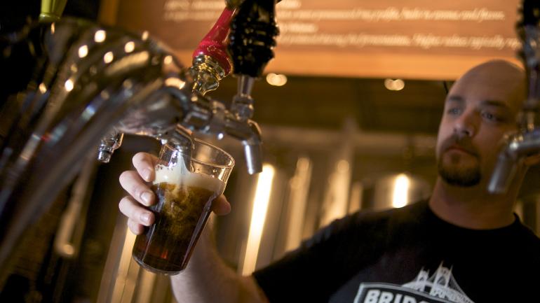 布里奇波特的酒保正在往杯子里装满精酿啤酒