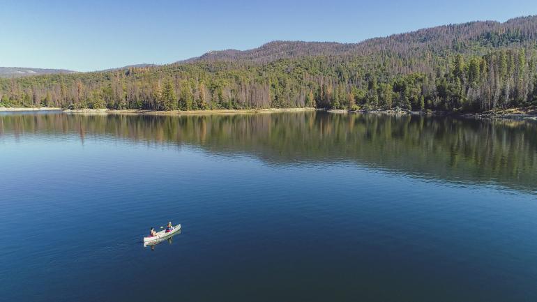 在加利福尼亚州马德拉县赛拉国家森林的巴斯湖上划独木舟
