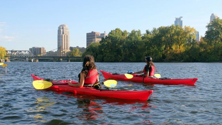 在明尼阿波利斯市中心的湖面上划皮划艇 在明尼阿波利斯市中心的湖面上划皮划艇
