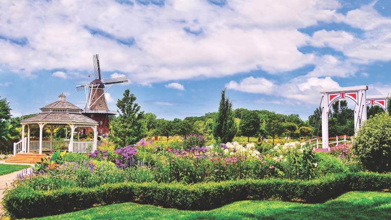 在风车岛花园上，五颜六色的鲜花争奇斗艳，掩映着荷兰风情的建筑细节