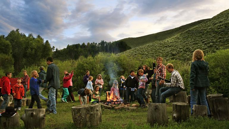 科罗拉多州观光牧场住宿期间在篝火旁享受音乐的家庭