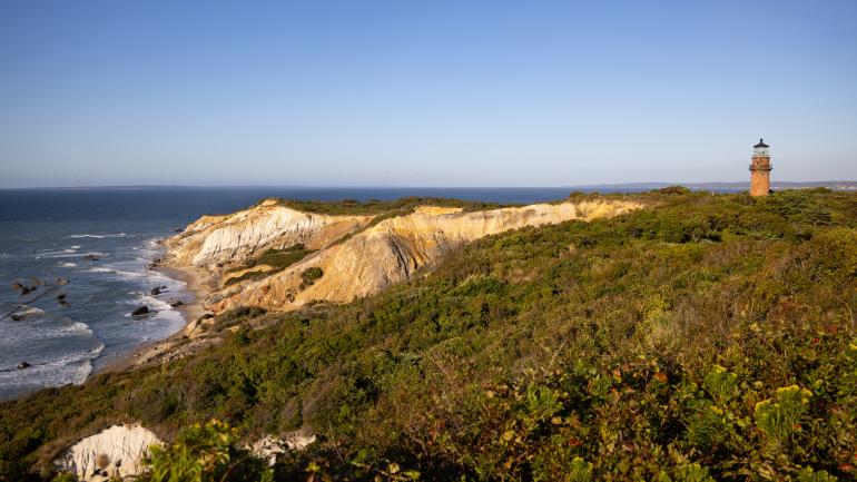 盖伊角灯塔遥望着玛莎葡萄园岛上风景如画的阿奎纳悬崖 盖伊角灯塔遥望着玛莎葡萄园岛上风景如画的阿奎纳悬崖