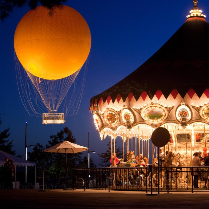 加利福尼亚州尔湾夜色下的光谱购物中心旋转木马与 Great Park 公园热气球