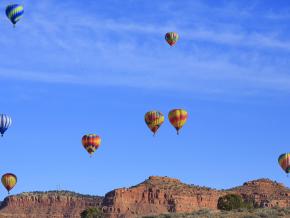 Hot air balloons soaring over the red rock Vermilion Cliffs