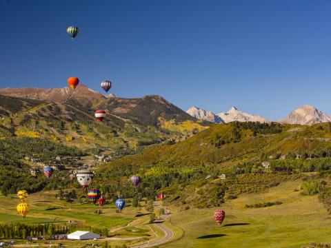 在科罗拉多州的斯诺马斯热气球节上，热气球漂浮在山地景观上