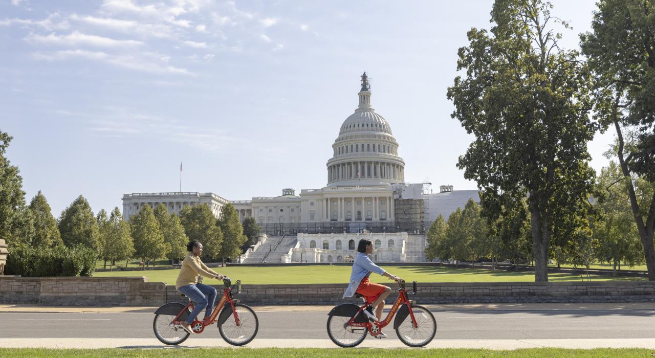 ワシントン D.C. のナショナルモールで、アメリカ国会議事堂の前を自転車で走り抜けます 