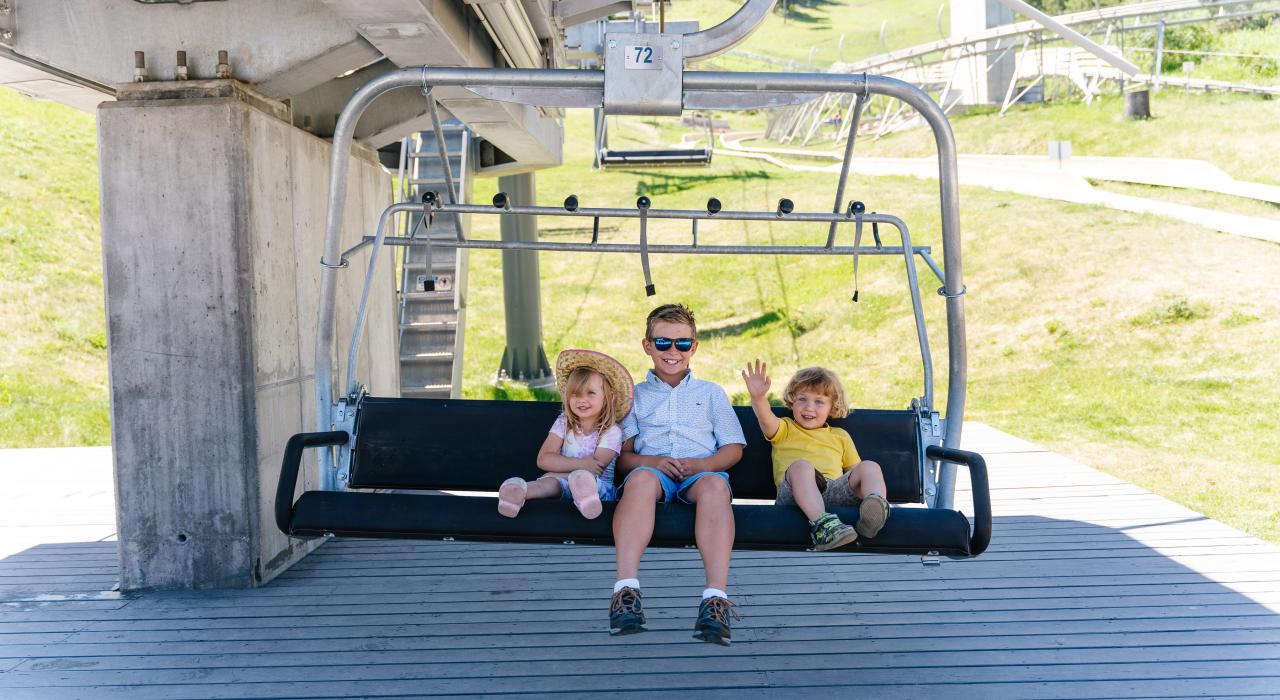 在怀俄明州杰克逊 Snow King Chair Lift 缆椅上笑容满面的三个孩子