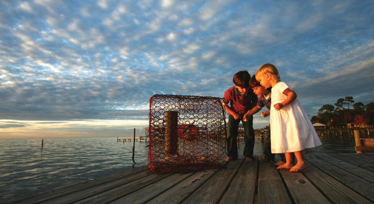 孩子们在阿拉巴马州莫比尔湾的码头上查看捕蟹笼