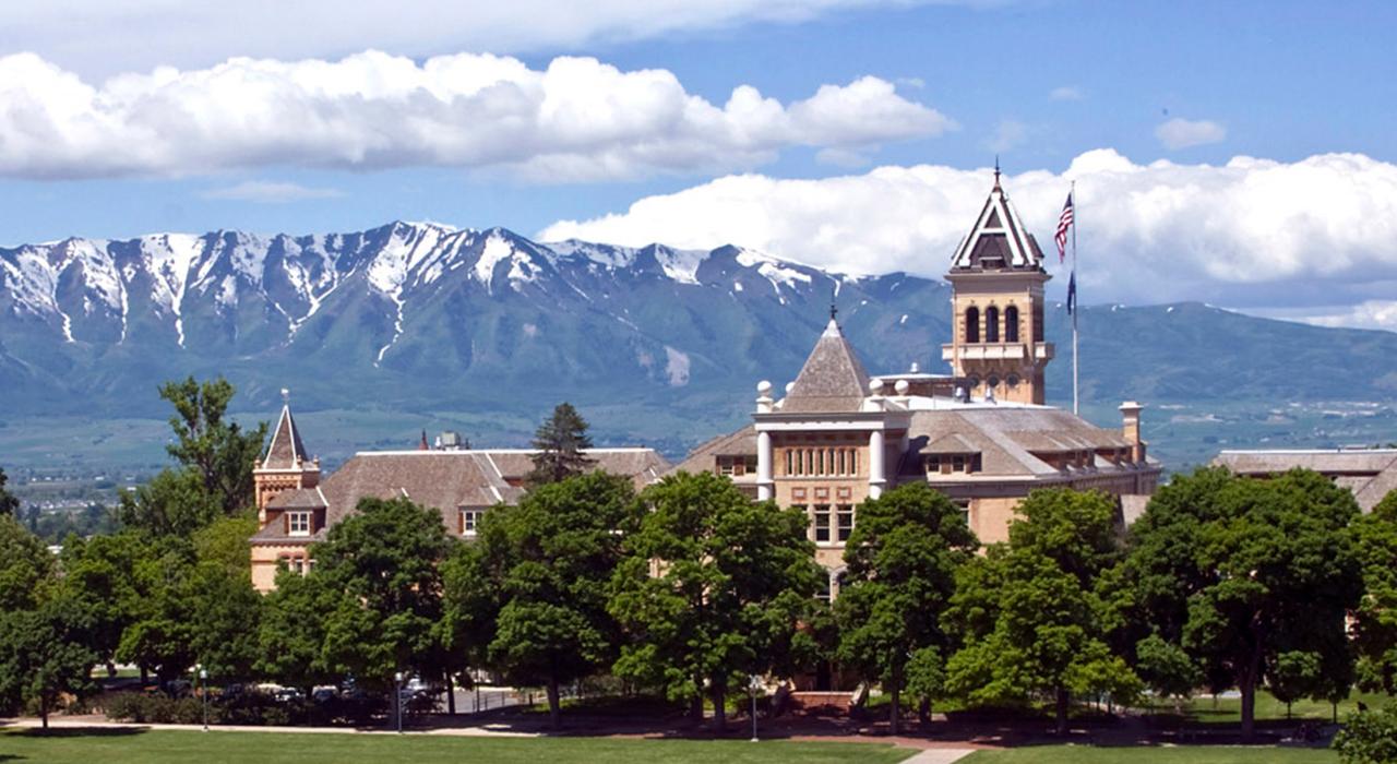 The Old Main Building at Utah State University with a snow-capped mountain backdrop