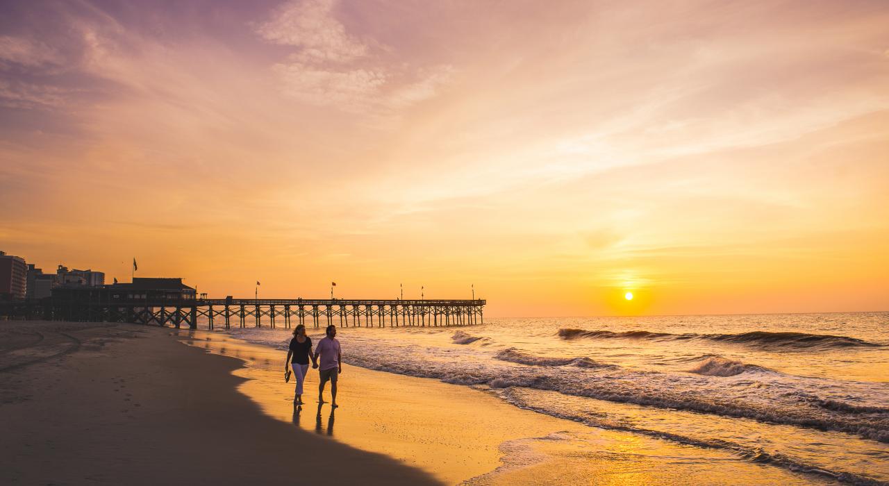 在美特尔海滩码头享受落日时光的一对爱人