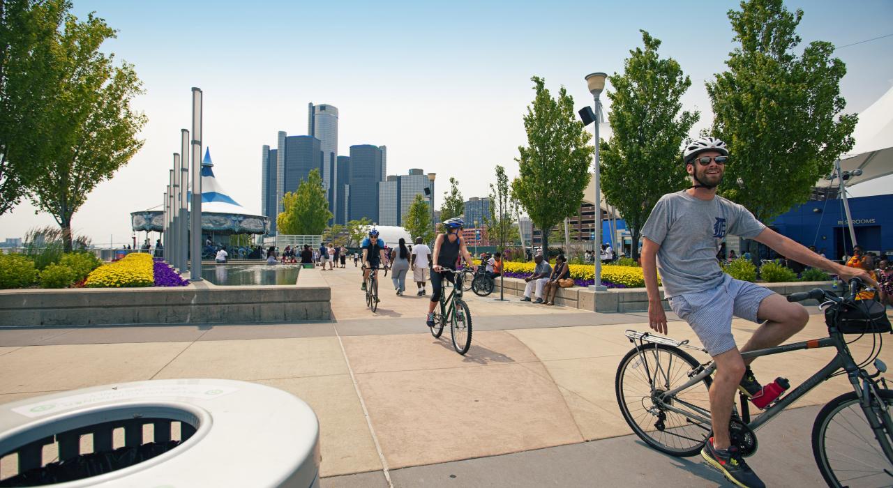 阳光灿烂的日子里骑自行车穿过 Rivard Plaza 广场海滨公园和花园