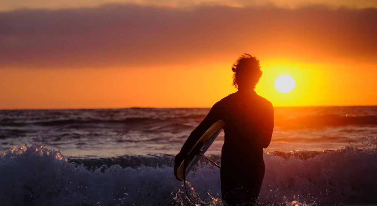 在 Strands Beach 海滩欣赏落日余晖的冲浪者