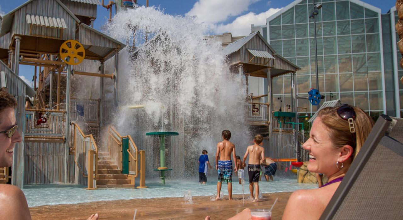 佛罗里达州凯西米，盖洛德棕榈度假酒店及会议中心的柏树泉水上乐园内，一对夫妇正在看孩子玩耍