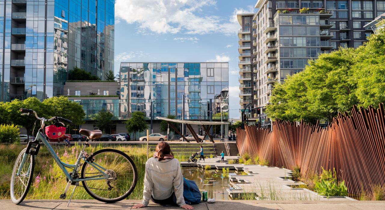 在生机勃勃的珍珠区,一位骑行者正在 Tanner Springs Park 公园惬意休息 在生机勃勃的珍珠区,一位骑行者正在 Tanner Springs Park 公园惬意休息
